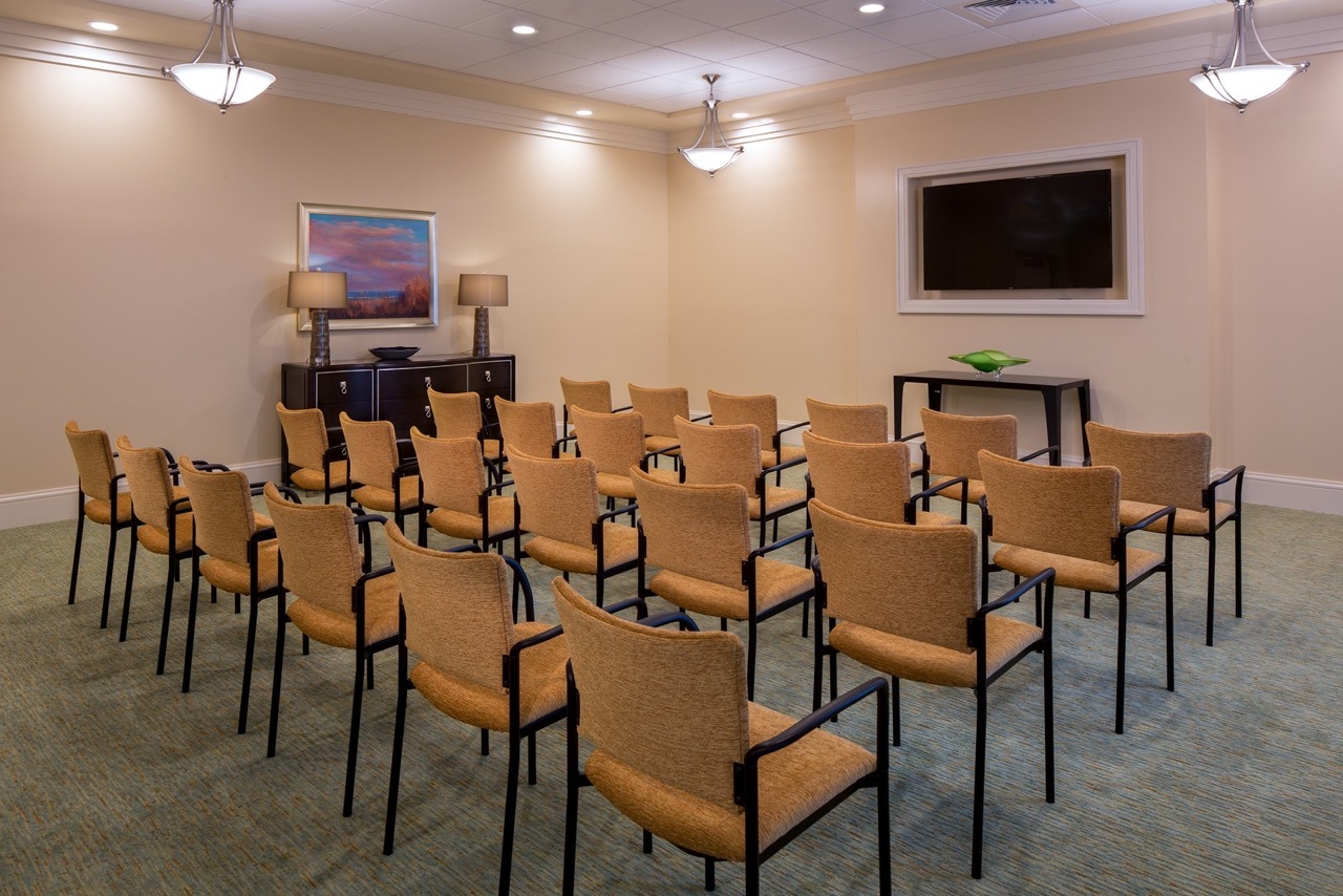 A movie theater room with rows of brown chairs placed facing the TV at The Summit of Lakewood Ranch.