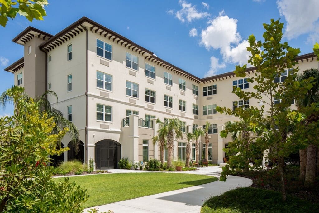 The Summit of Lakewood Ranch front building with palm trees and a pathway leading to it through the green.