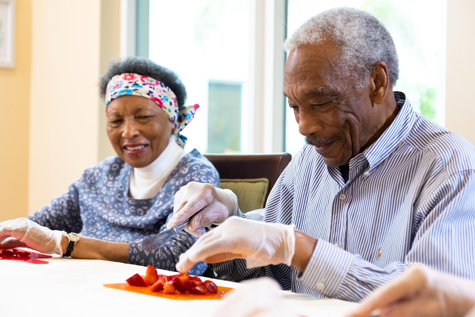 Two residents cutting strawberries during a cooking activity at The Summit of Lakewood Ranch, a senior living community.