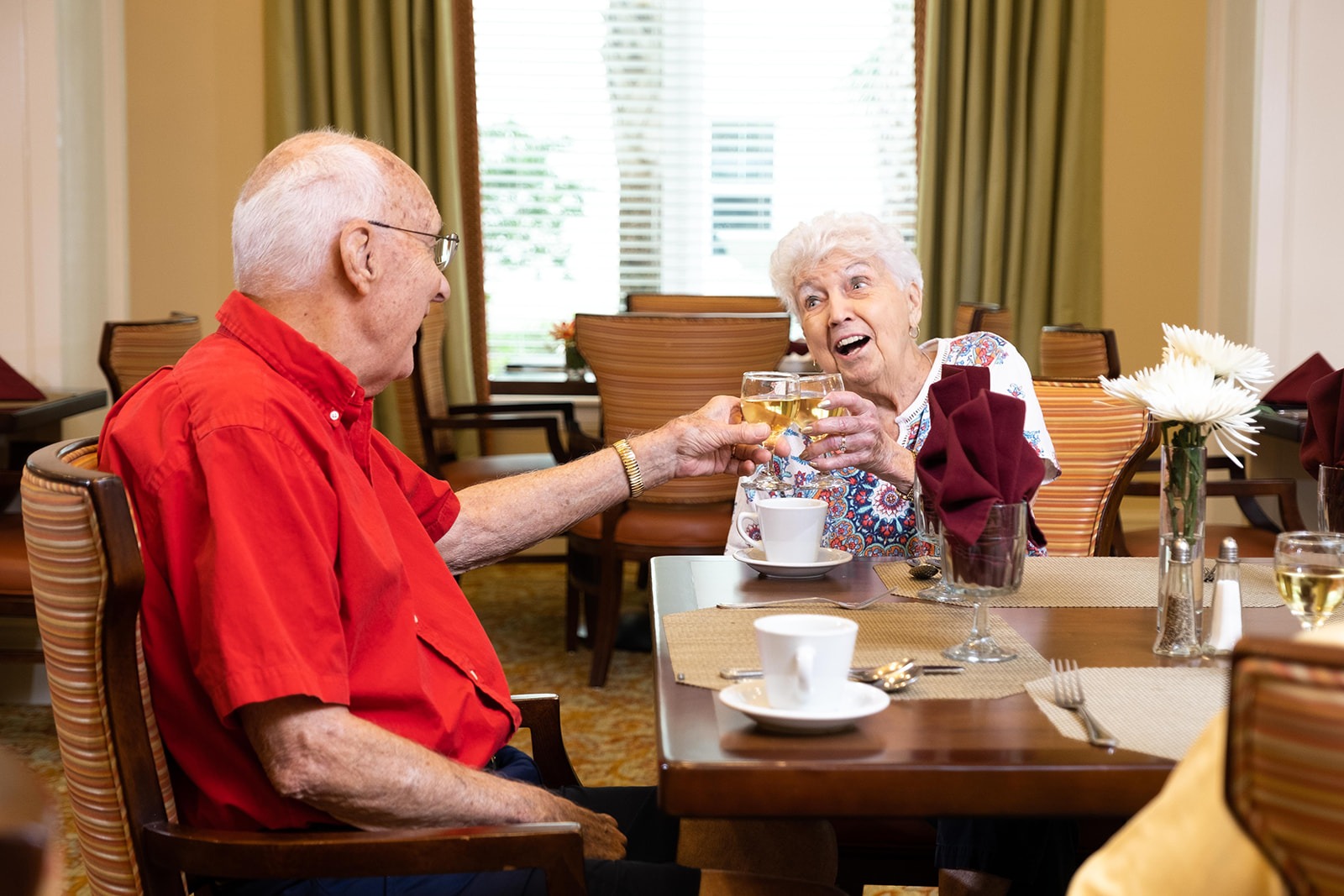 Lakewood Ranch - The Summit of Lakewood Ranch A happy resident toasting with a friend in the dining room atThe Summit of Lakewood Ranch, a top senior living choice.